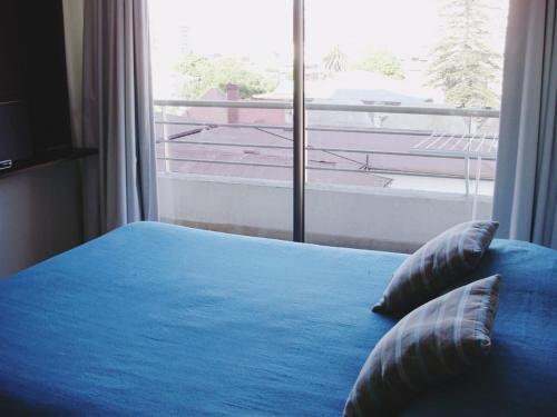 a bed with blue sheets and pillows in front of a window at Departamento acogedor con excelente ubicación in El Cerrillo