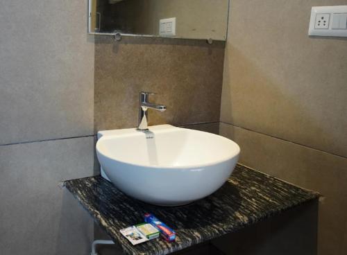 a white bowl sink on a counter in a bathroom at Hotel Janani Mansion in Mysore