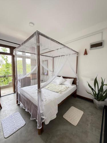 a bedroom with a canopy bed with white sheets and pillows at Olaia Apartments and Cafe in Weligama