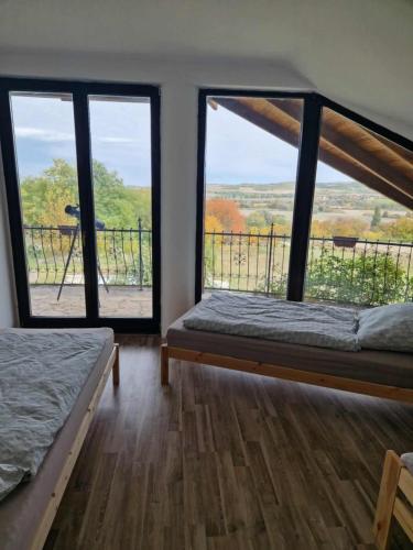 a bedroom with two beds and a large window at Szelek Palotája in Écs