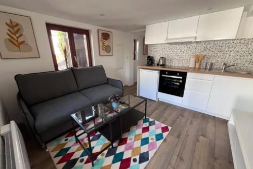 ein Wohnzimmer mit einer schwarzen Couch und einer Küche in der Unterkunft Soh Rent Appartement Schiltigheim proche Strasbourg terrasse -Tv in Schiltigheim