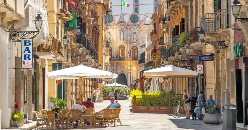 a group of people sitting under umbrellas on a city street at Cattedrale Central Rooms in Palermo