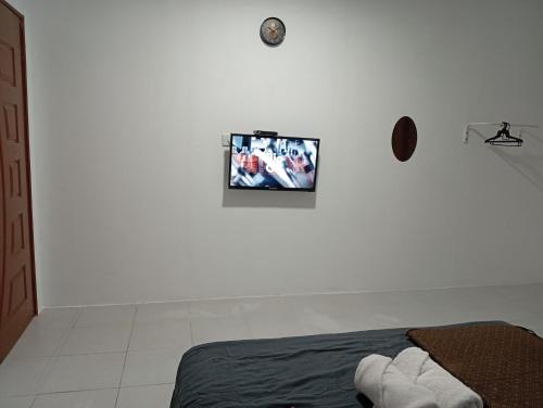 Un dormitorio con un televisor colgado en una pared blanca. en RoomStay Changloon Berhawa Dingin dan Privasi Penuh, en Changlun