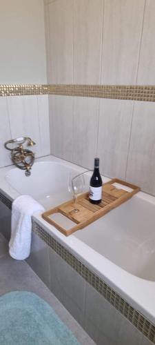 ein Holztablett mit einer Flasche und einem Weinglas auf einer Badewanne in der Unterkunft The Throne in Johannesburg