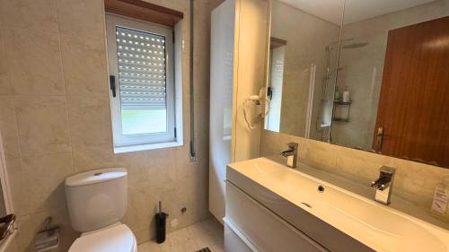 Un baño con inodoro, lavabo y espejo. en Lourença Stays - Vila Beach Apartment, en Vila do Conde