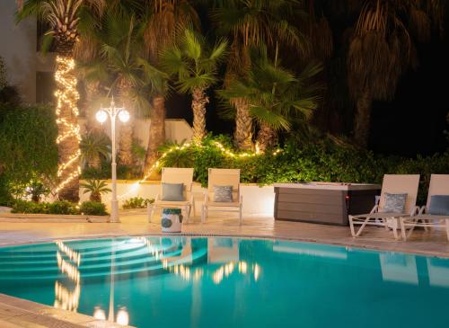 - une piscine avec des chaises et des lumières la nuit dans l'établissement Villa Alexandra: Sea Views Pool Jacuzzi Sauna, à Mellieħa
