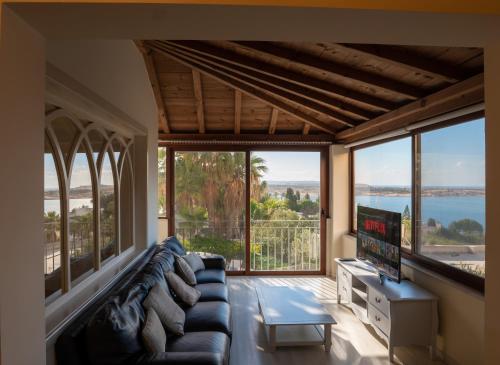 a living room with a couch and a tv at Villa Alexandra: Sea Views Pool Jacuzzi Sauna in Mellieħa