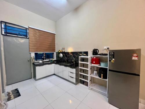 a kitchen with a stainless steel refrigerator and white tile floors at KNH Homestay in Kangar