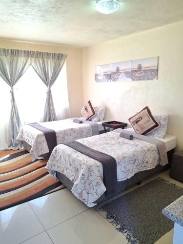 a bedroom with two beds and a window at Cosy Beds Web in eMalahleni