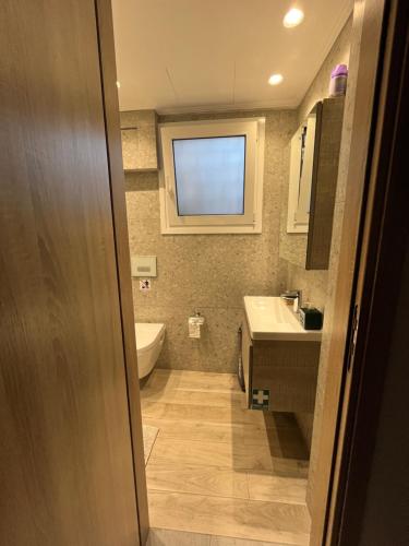 Un baño con lavabo, inodoro y ventana. en AA seaside apartment, en Artemida