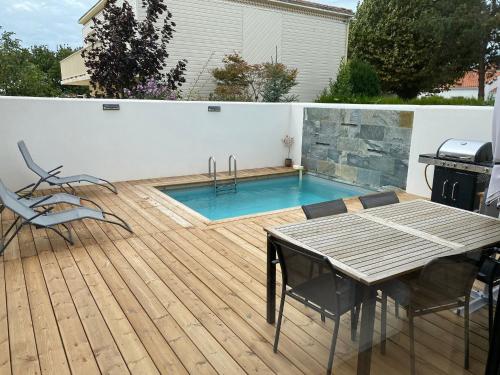 a pool with a table and chairs on a wooden deck at superbe villa neuve in Aytré