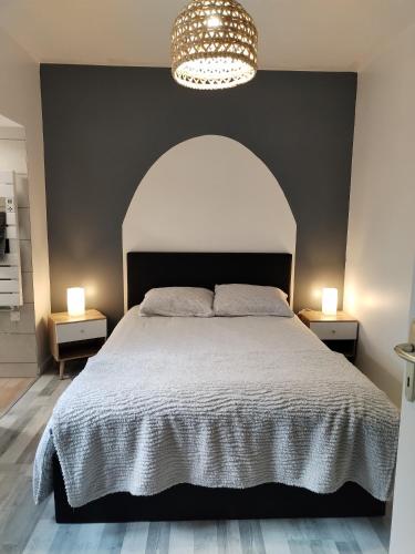 a bedroom with a large bed with a black headboard at Appartement Cosy in Louhans