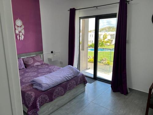 a bedroom with a purple bed and a large window at Heaven on earth! in Grand Gaube