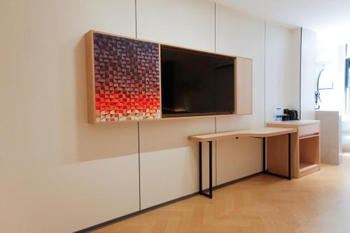 a room with a tv on a wall with a table at HuaHang Hotel - Free Shuttle&Free Breakfast - Guangzhou Baiyun International Airport in Guangzhou