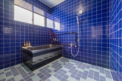 a blue tiled bathroom with a sink and a shower at 一棟貸しハウスまれち in Kumejima