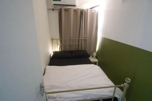 a small room with a bed and a green wall at Downtown Private room in Abu Dhabi
