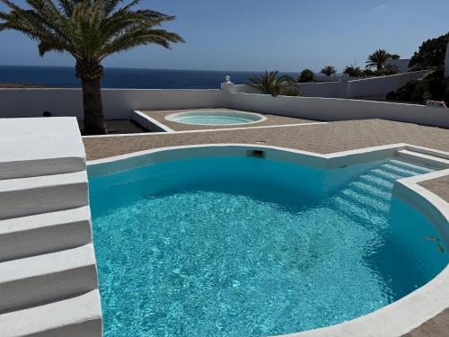 una piscina nel mezzo di un patio con vista sull'oceano di Finca PiedraNegra a Tías