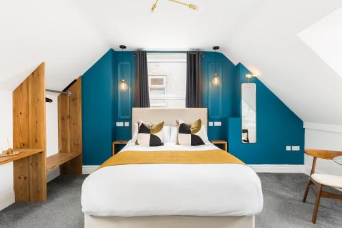 a bedroom with a large bed with blue walls at The Adelphi Aparthotel in Stratford-upon-Avon