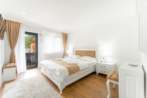 a white bedroom with a large bed and a window at Pensiunea Suci in Botiza