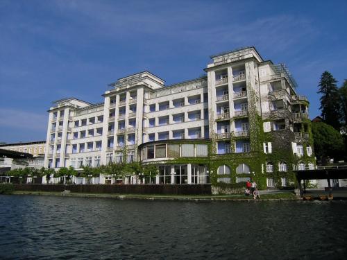 a large building with ivy on the side of a river at Grand Hotel Toplice - Small Luxury Hotels of the World in Bled