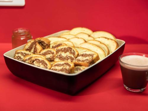 hotelF1 Paris Gennevilliers, 4 Rue Georges Corète 92230 Gennevilliers في جينفيليي: صينية خبز على طاولة حمراء مع مشروب