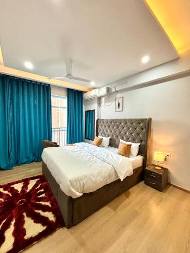 BadgomEvoque Suites的卧室里有一张带蓝色窗帘的大床