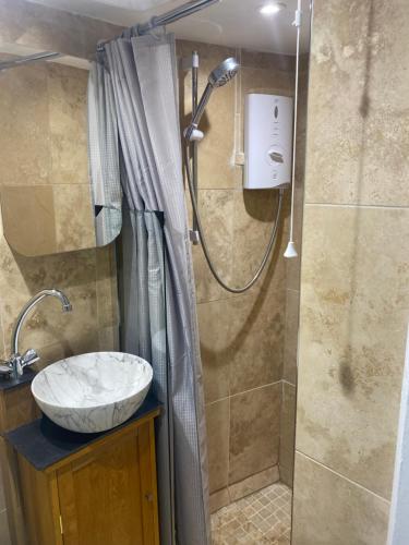 ein Badezimmer mit Waschbecken und Dusche in der Unterkunft Cosy cottage in Torquay