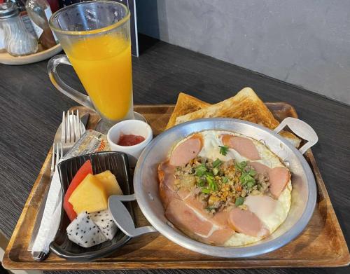 una bandeja con un tazón de comida y un vaso de jugo de naranja en ณิชาวิลล่า ริเวอร์ฟร้อนท์ บ้านท่าตอน Nicha Villa Riverfront BanThaton, en Mae Ai Chiang Mai