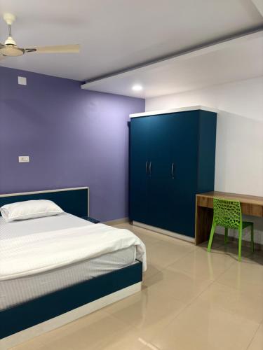 a bedroom with blue walls and a bed and a desk at Zarica Homestay in Kannur