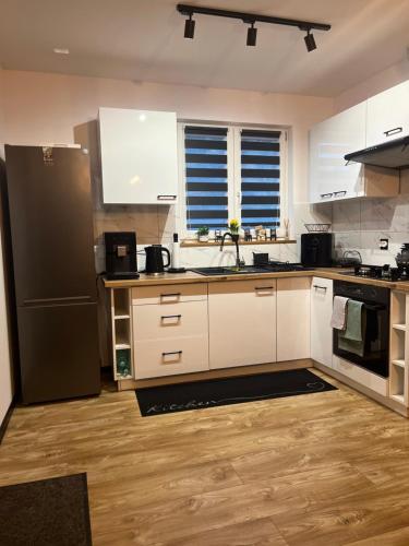 ルドビコビツェ・クウォツキエにあるNest Hausの白いキャビネットと黒い冷蔵庫のあるキッチン