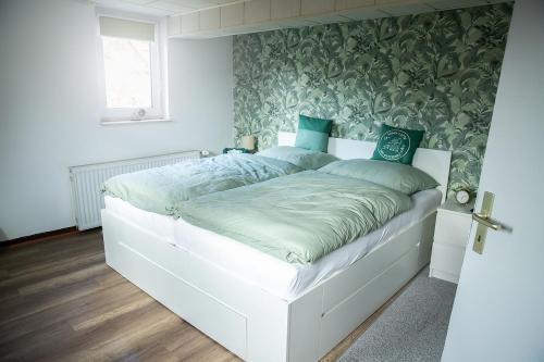 a white bed in a bedroom with green and white wallpaper at Ferienhaus Lotte in Vöhl