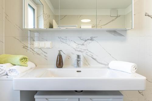 a white bathroom with a sink and a mirror at Touch Upon Metropolis by JR City Apartments in Gerasdorf bei Wien