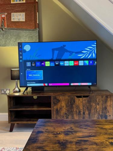 a flat screen tv sitting on top of a wooden stand at Stunning house in Chorlton in Manchester