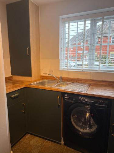 a kitchen with a sink and a washing machine at Stunning house in Chorlton in Manchester