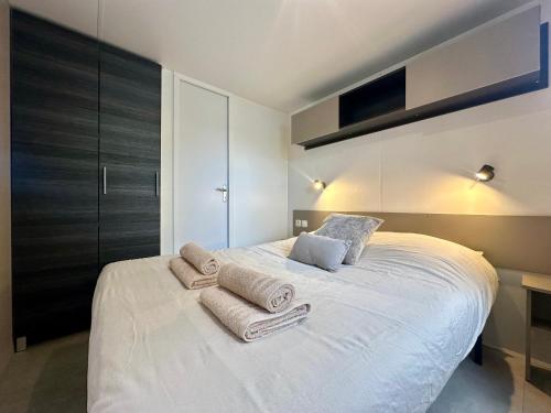 a bedroom with a white bed with towels on it at Mobil-home camping 4 étoiles à Valras-Plage Clim Piscine Proche Mer 6 à 8 pers in Valras-Plage