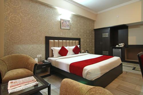 Habitación de hotel con 1 cama y 2 sillas en Le Grand Hotel, en Haridwar