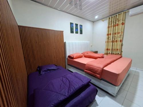 two beds in a bedroom with purple and orange sheets at Bahrin Homestay Lampung in Kedaton