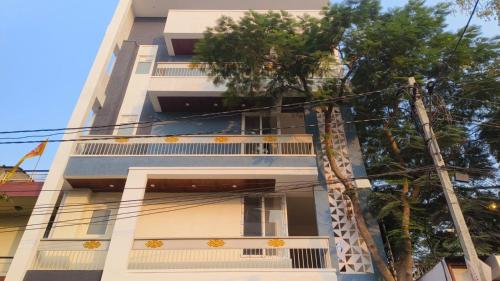 ein hohes weißes Gebäude mit Bäumen davor in der Unterkunft Hostro Stays in Jaipur