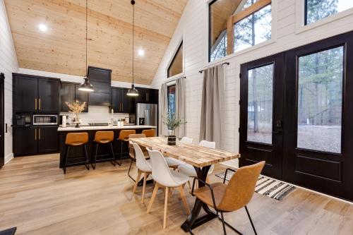 une cuisine et une salle à manger avec une table et des chaises en bois dans l'établissement Crimson Creek Cabin - Hot Tub, Playset, Family-Friendly, à Broken Bow