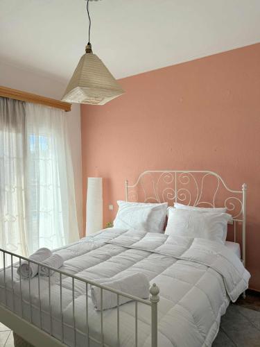 a bedroom with a white bed with a pink wall at Casa Verde Trikala in Tríkala