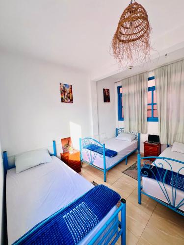 a bedroom with two beds and a chandelier at TISLIT Surf Taghazout in Taghazout