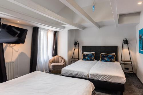 a hotel room with two beds and a chair at Hotel Pauw in Nijmegen