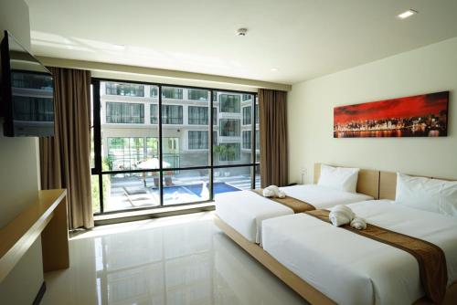 two beds in a room with a large window at Beston Pattaya - SHA Plus Certified in Pattaya South