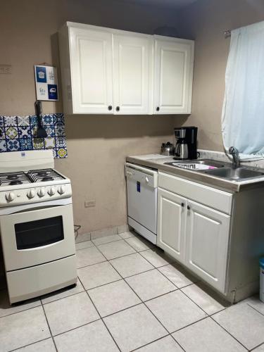 La cuisine est équipée de placards blancs, d'une cuisinière et d'un évier. dans l'établissement Casitapp punto com punto mx, à Tijuana