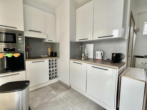 a white kitchen with white cabinets and appliances at L'Appartement du Port in Étaples