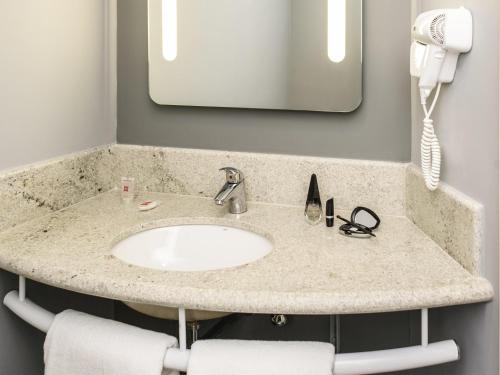 - un comptoir de salle de bains avec un lavabo et un téléphone dans l'établissement ibis Recife Aeroporto, à Récife