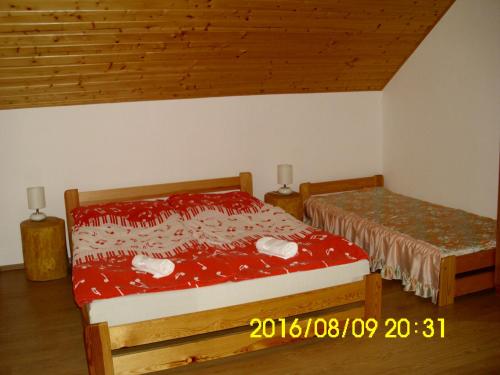 a bedroom with two beds with red sheets and wooden ceilings at Apartmány nad Otavou in Zvíkovské Podhradí