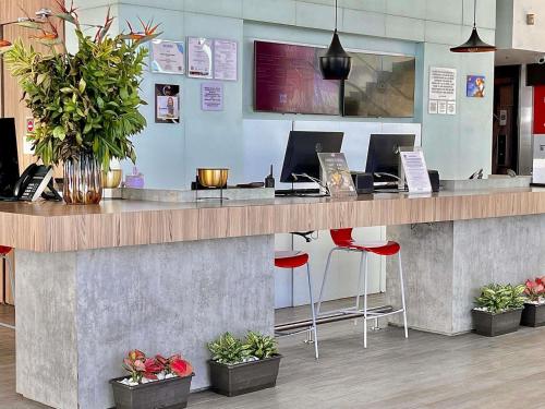 a lobby with a counter with two computers and plants at ibis Cartagena Marbella in Cartagena de Indias
