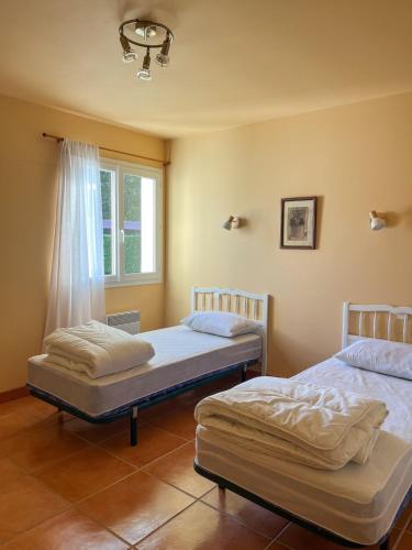 two twin beds in a room with a window at Maison chaleureuse in Mézos