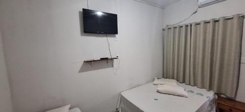 Cette chambre blanche dispose d'une télévision murale. dans l'établissement Turis Hotel, à Dourados